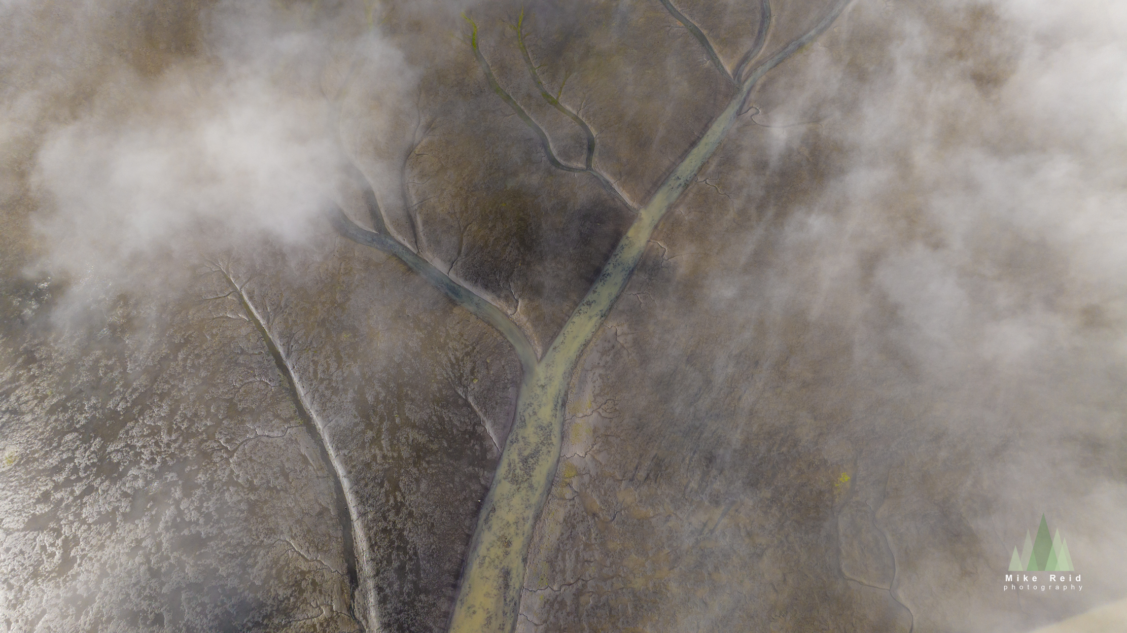Aerial braided river channels with misty texture and muted tones, Iceland